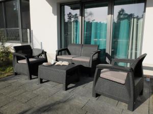 eine Gruppe von Stühlen und Tischen auf einer Terrasse in der Unterkunft Apartament 33BalticBlue in Pogorzelica