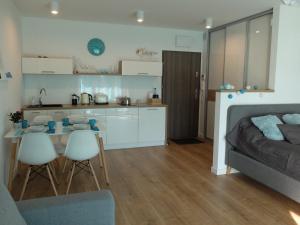 ein Schlafzimmer mit einem Bett und eine Küche mit einem Tisch und Stühlen in der Unterkunft Apartament 33BalticBlue in Pogorzelica + 10 Fotos