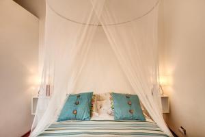 a white canopy bed with blue pillows in a bedroom at Elegant Apartment Behind the Colosseum in Rome