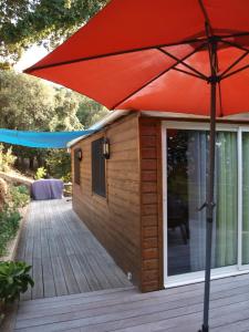 a large red umbrella sitting on a wooden deck at Le petit chalet in Porticcio