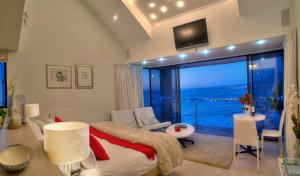 a hotel room with a large bed and a large window at 185 on BEACH Boutique Suites in Gordonʼs Bay