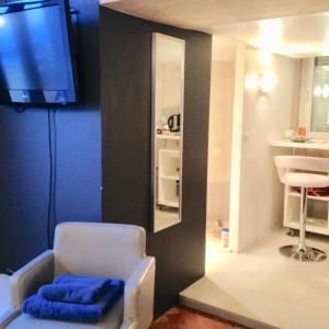 Habitación con silla, TV y baño. en appartement Monaco Beausoleil, en Beausoleil