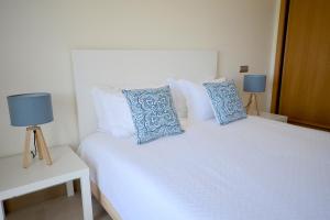 een slaapkamer met een wit bed met blauwe kussens bij Millennium Golf Residences in Vilamoura +14 foto's