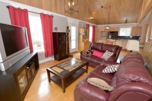 een woonkamer met lederen meubels en een flatscreen-tv bij Paradis du Lac Nairne in Notre-Dame-des-Monts