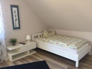 a small bedroom with a white bed and a night stand at Ferienwohnung am Dörenberg in Georgsmarienhütte