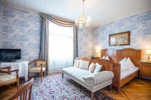 ein Schlafzimmer mit einem Bett, einem TV und einem Sofa in der Unterkunft Villa Excelsior Hotel & Kurhaus in Bad Gastein