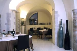 restauracja z białymi stołami, czarnymi krzesłami i wazami w obiekcie Hotel Orazio w mieście Venosa