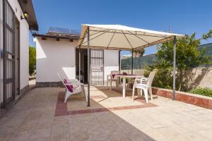 eine Terrasse mit einem Tisch und Stühlen unter einem Sonnenschirm in der Unterkunft Giardino del Teatro, casa vacanze immersa nel verde in Syrakus