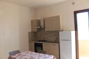 a kitchen with a table and a white refrigerator at Residenza Santoro in Melendugno +7 photos