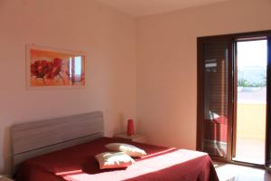 una camera da letto con un letto con lenzuola rosse e una finestra di Residenza Santoro a Melendugno