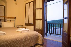 a bedroom with a bed and a balcony with a view at Tholos in Áno Dholianá
