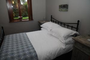 łóżko z białą pościelą i poduszkami w sypialni w obiekcie Ty Carreg Fach Staycation Cottage Cardiff w Cardiff