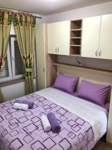 ein Schlafzimmer mit einem lila und weißen Bett mit lila Kissen in der Unterkunft Apartments Galic in Šibenik