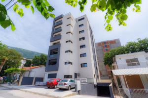 a tall white building with cars parked in front of it at N Apartments in Sutomore