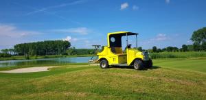 a yellow tractor parked on a golf course at Hanna Apartman in Bük