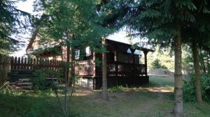 a log cabin with a fence and trees at Domek letniskowy w Rygoli in Rygol