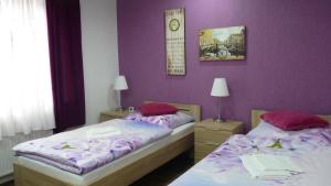 two beds in a room with purple walls at Hotel Rodizio UG in Wolfsburg