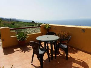 una mesa y sillas en un balcón con vistas al océano en Casas Los Abuelos De Calderon, en Icod el Alto