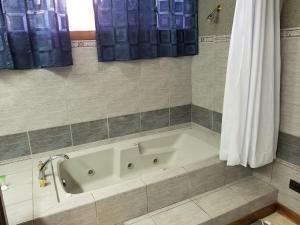 a bath tub in a bathroom with blue curtains at Hotel Monte Campana Escazu in San José +85 photos
