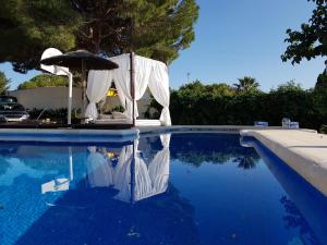 una piscina con sombrilla, mesa y sillas en El chalet del Mar, en Chiclana de la Frontera