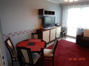a living room with a table and a television at Apartament Nad Czosem in Mrągowo