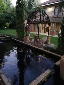 a pond in front of a house with a gazebo at Giardino a 194 in Welkom