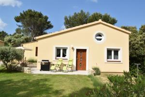 a small yellow house with four chairs in a yard at ACCENT IMMOBILIER Villa neuve wifi gratuit piscine in Orgon
