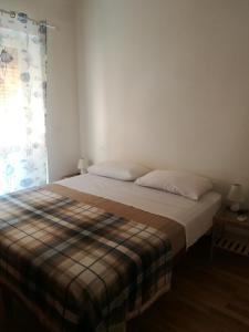 a bedroom with a bed with a plaid blanket and a window at Costaguta Apartment in Rapallo