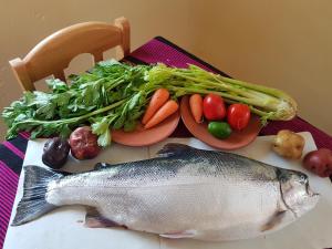 a table with a fish and vegetables on a table at Musqoy Wasi de Gonzalo in Ocosuyo