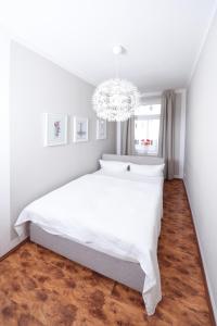 ライプツィヒにあるApartments-Leipzigのベッドルーム(白いベッド1台、シャンデリア付)