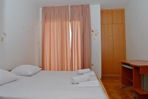 a bedroom with a large white bed and a desk at Apartments Mačak in Novalja