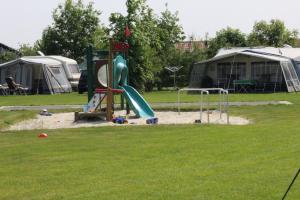 a playground with a slide and tents in a field at Tiny Cottage op Camping "De stal" in Drijber