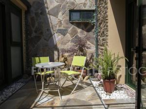 a patio with a table and chairs and a stone wall at Pension Siete en el Camino in Sarria
