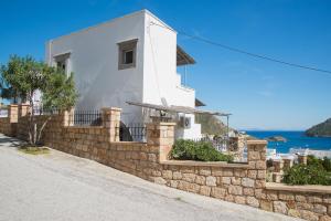 a white house with a stone wall at Captain Manos Studio Apartments in Grikos