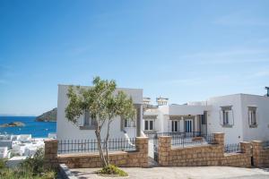 une villa blanche avec un arbre en face de l'océan dans l'établissement Captain Manos Studio Apartments, à Grikos