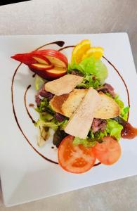 um prato branco com uma salada com queijo e tomates em Hotel Le St Jean em Beaumont-de-Lomagne