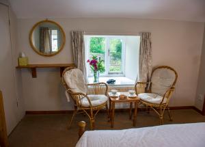 a bedroom with two chairs and a table and a window at Rye Hill Farm in Hexham