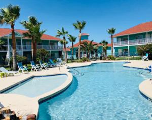 - une piscine dans un complexe avec des palmiers dans l'établissement Days Inn by Wyndham Port Aransas TX, à Port Aransas
