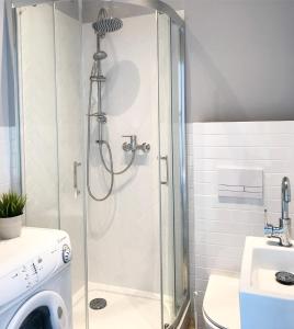 a shower with a glass door in a bathroom at Apartamenty Nadmorska in Rowy