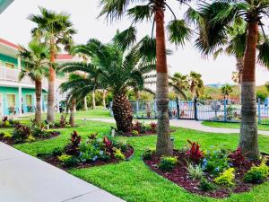 un parc avec des palmiers et des fleurs dans l'herbe dans l'établissement Days Inn by Wyndham Port Aransas TX, à Port Aransas