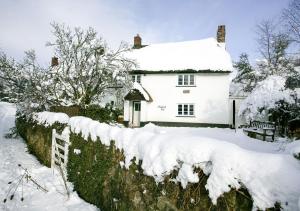 a white house covered in snow with a fence at Moorland View Cottage in North Bovey