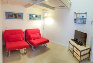 duas cadeiras vermelhas num quarto com uma televisão em Blue Bay Taormina em Taormina