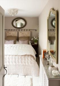 a bedroom with a white bed and a mirror at Moorland View Cottage in North Bovey