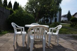 three white chairs and a white table in a yard at Apartamenty z klimatem in Poznań