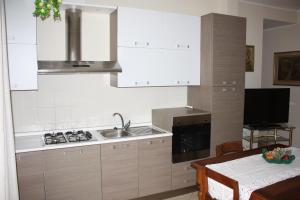 チェルタルドにあるCasa Bettaの白いキャビネット、シンク、テーブル付きのキッチンが備わります。