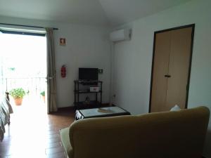 ein Wohnzimmer mit einem Sofa und einem TV in der Unterkunft Residencial Retiro Sra. da Luz in Ponte de Lima