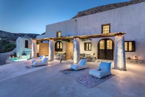 an outdoor patio with white chairs and a building at Canava Villas #3 in Santorini in Emporio