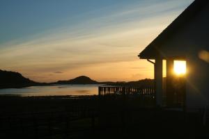 ein Haus mit Sonnenuntergang im Hintergrund in der Unterkunft The Galley Of Lorne Inn in Ardfern