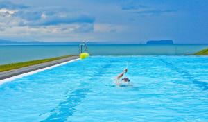 
a person jumping in the water with a frisbee at Sunnuberg Guesthouse in Hofsós
