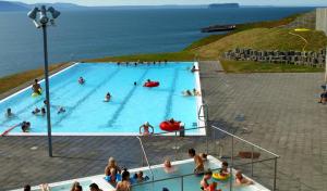 a large swimming pool with people in the water at Sunnuberg Guesthouse in Hofsós